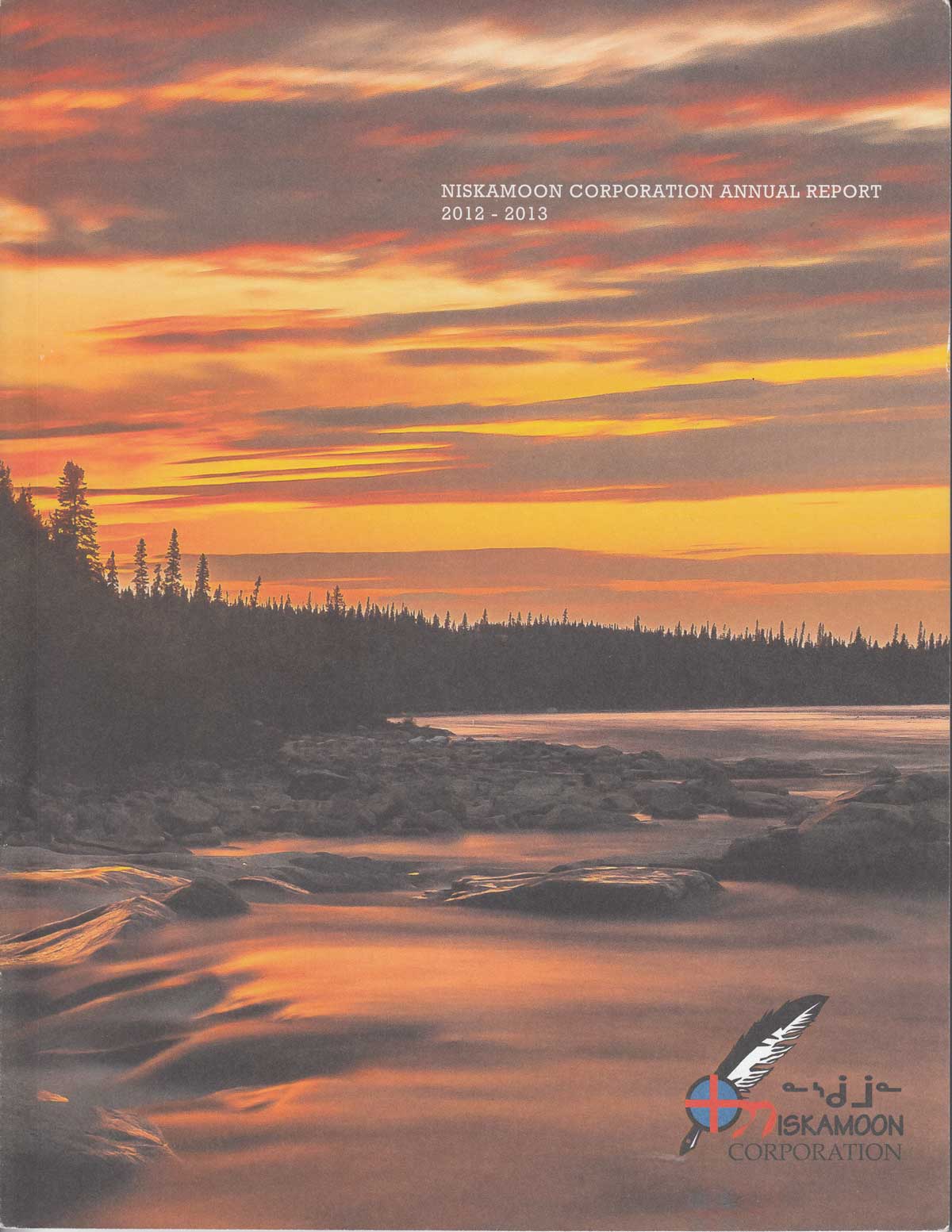 A vibrant sunset with orange and yellow clouds over a calm river bordered by pine trees, featured on the cover of the Niskamoon Corporation 2012-2013 Annual Report. Niskamoon’s logo appears at the bottom right corner.